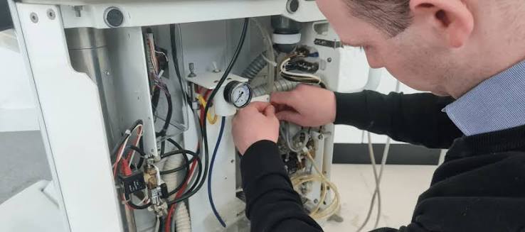 A Precision Dental engineer servicing the internal components and pressure gauge of a dental unit