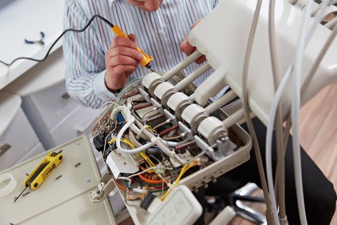 A Precision Dental engineer working on the internal pipework and wiring of a dental delivery unit